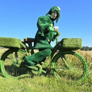 Gerda Gras –                                                                                                                        Grasdame auf Grasfahrrad